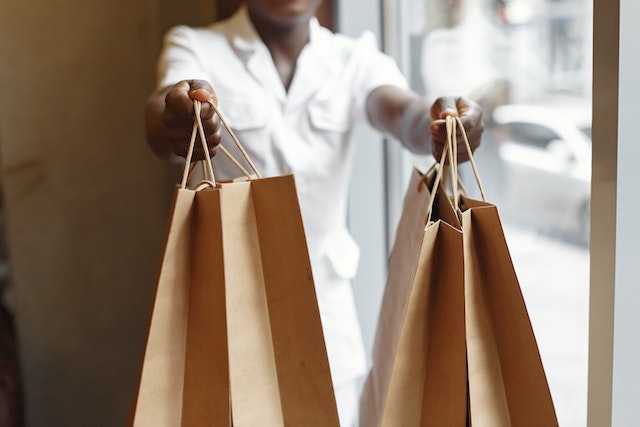 A woman holds out two shopping bags