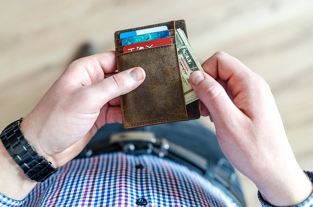 A man holding a wallet with cards and cash inside.