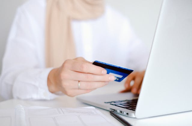 Woman in white shirt holding credit card during the checkout process while online shopping 