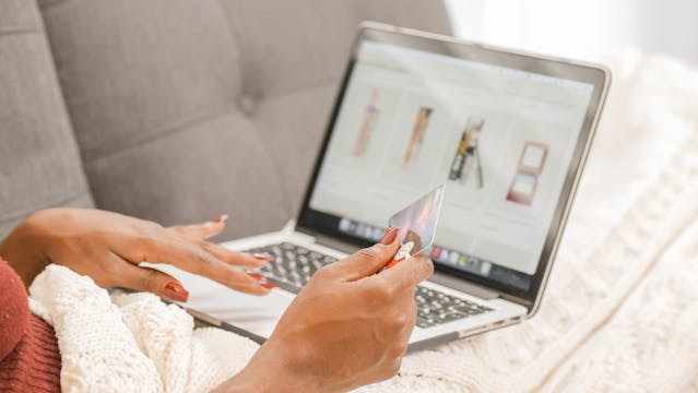 A person holding their card ready to make an online purchase on their laptop.