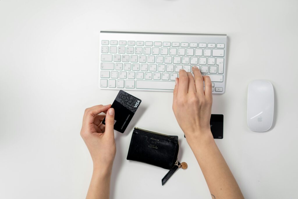 Woman with wallet types in credit card details on a keyboard