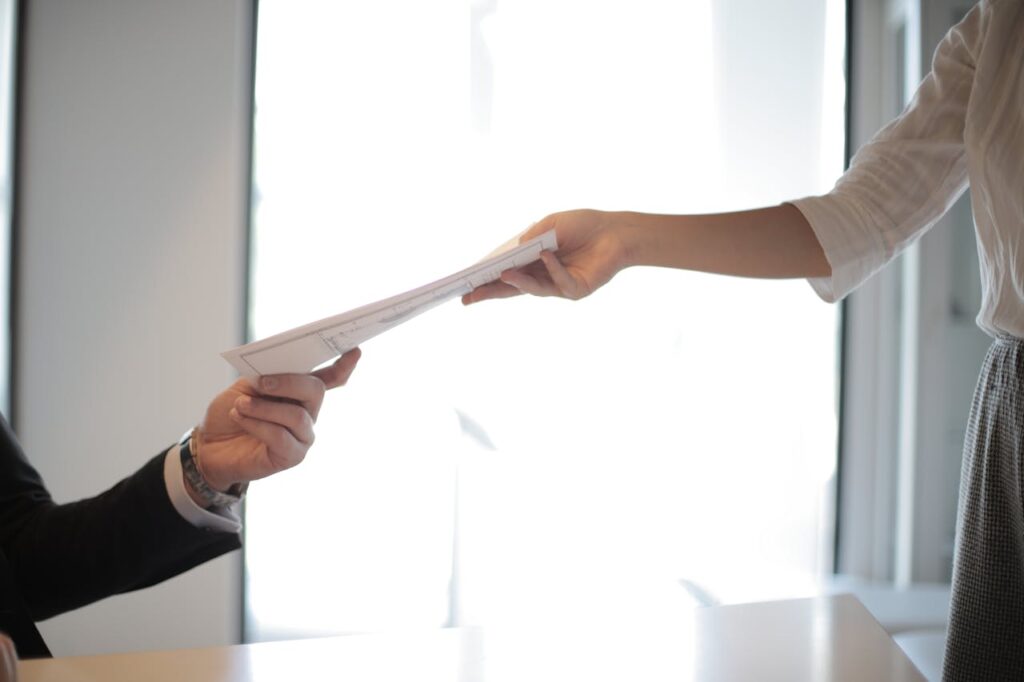 A potential job candidate hands over her resume to a business employer