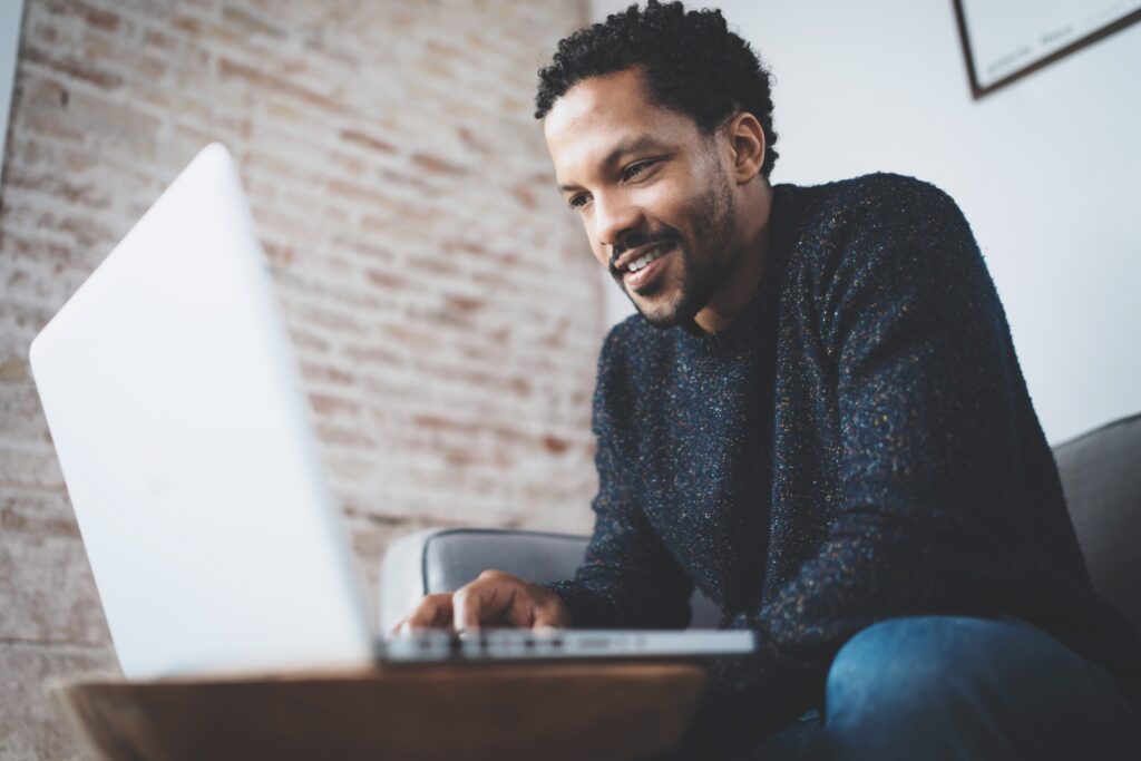 A smiling man looking at a laptop after utilizing e-commerce optimization for his business