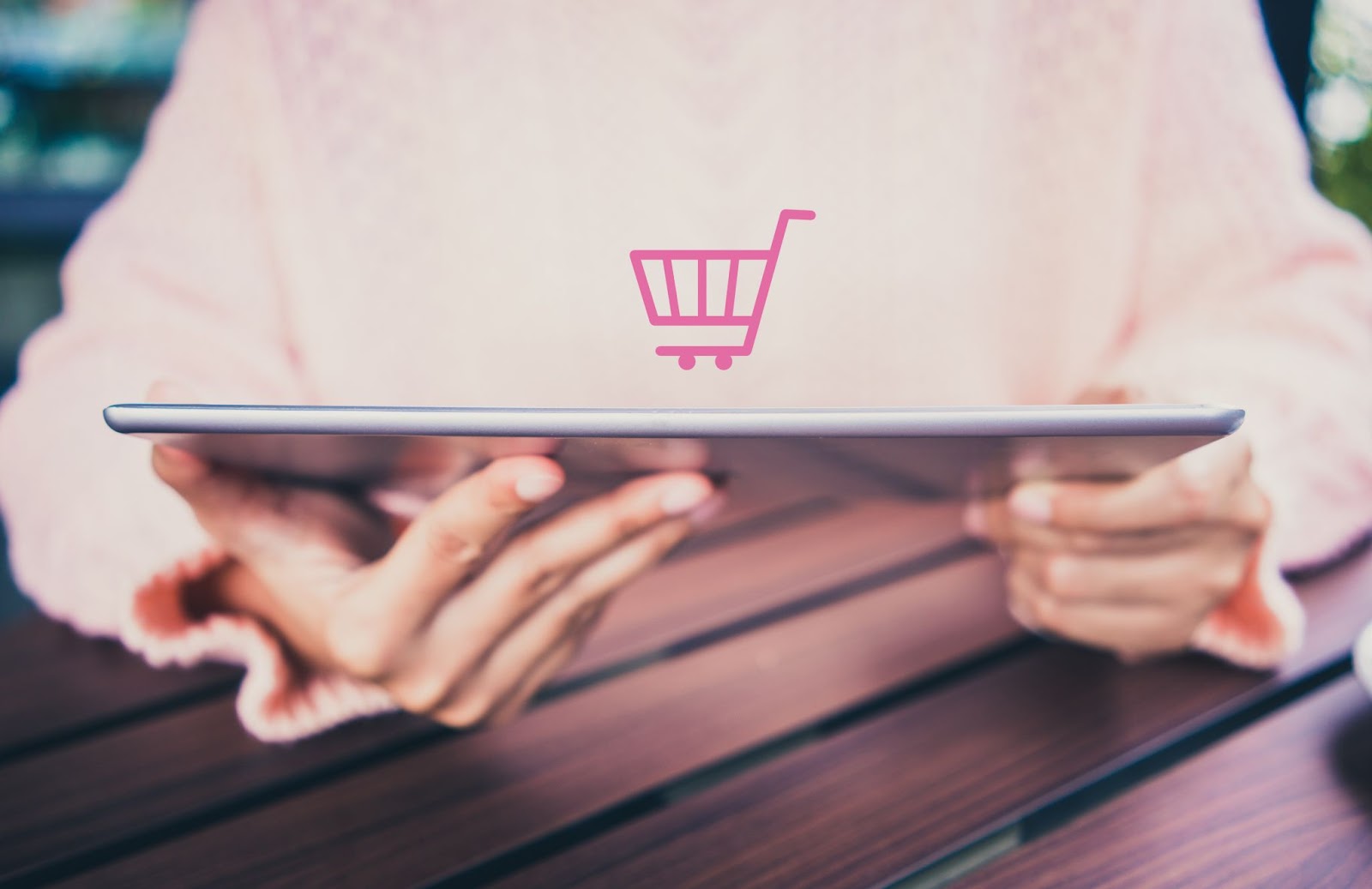 A woman on an iPad with a logo representing an e-commerce shopping cart