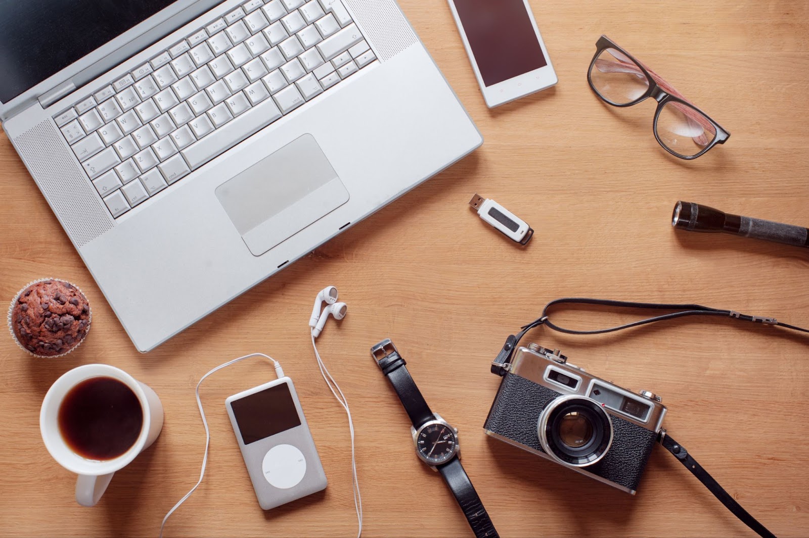 A laptop next to a camera, iPod, and other tools for using digital products